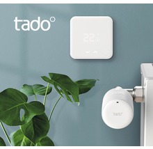 Logo Tado, nástěnný termostat a hlavice radiátoru na zdi