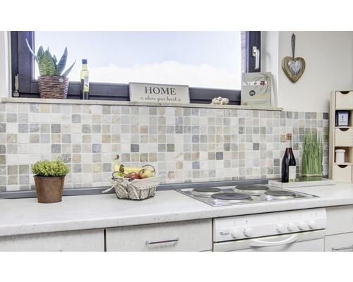 Kuchyňská scéna s mozaikovými obklady, mísou s ovocem, varnou deskou a dekorací