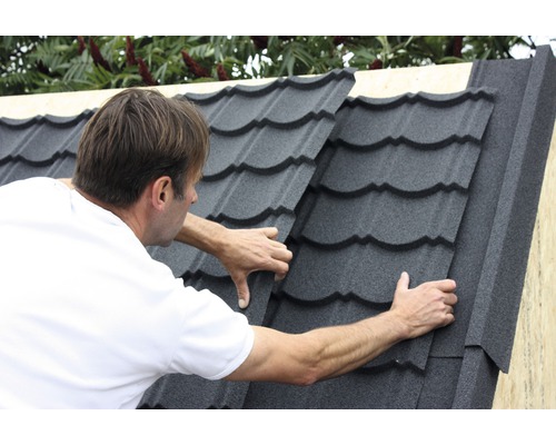 Muž pokládá střešní tašky na střechu