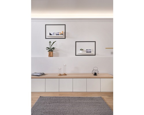 Obývací pokoj s dřevěnou podlahou, šedým kobercem, příborníkem a nástěnnými policemi