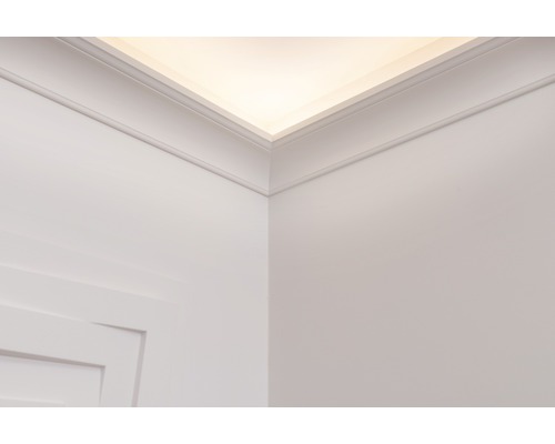 Pohled na stěnu a strop s ozdobnými lištami a nepřímým osvětlením