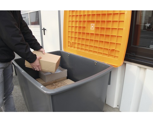 Osoba vkládá balíky do šedé nádoby na recyklaci s otevřeným oranžovým víkem