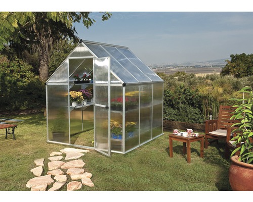 Skleník s policemi a otevřenými dveřmi na zahradě.