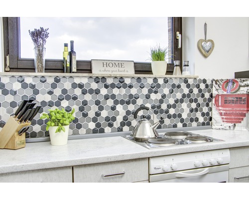 Kuchyňská scéna s mozaikovými dlaždicemi ve tvaru šestiúhelníků, sporákem a kuchyňským náčiním.