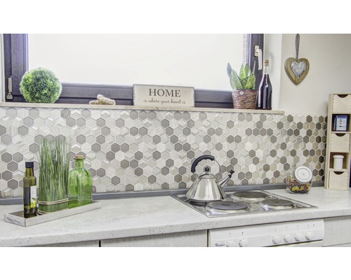 Kuchyňská scéna s mozaikovými dlaždicemi v šestiúhelníkovém vzoru, varnou deskou a dekoracemi.