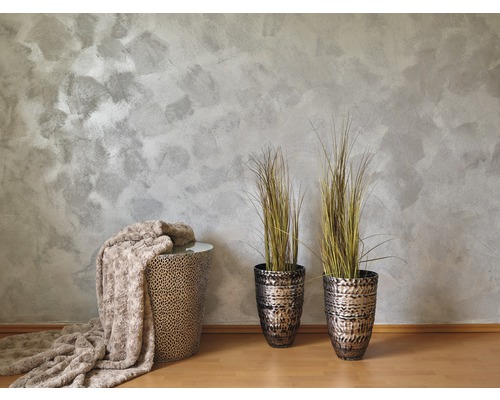 Dekorativní scéna s odkládacím stolem, dekou a rostlinami v květináčích před vzorovanou stěnou