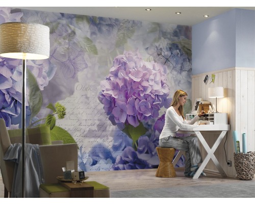 Obývací pokoj s květinovou tapetou, psacím stolem a sedící ženou