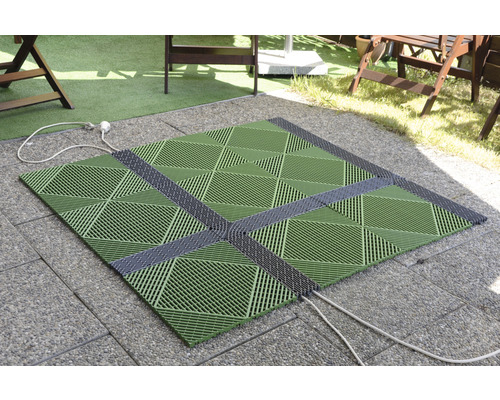 Čtvercové, zelené terasové dlaždice se šedými spojovacími prvky na dlážděném podkladu venku