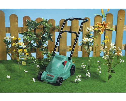 Sekačka na trávu Bosch na trávníku před dřevěným plotem a květinami