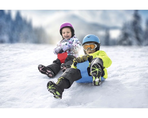 Dvě děti bobují na sněhu s mini bobem.