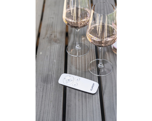 Dvě plné sklenice na víno a dálkové ovládání na dřevěném stole