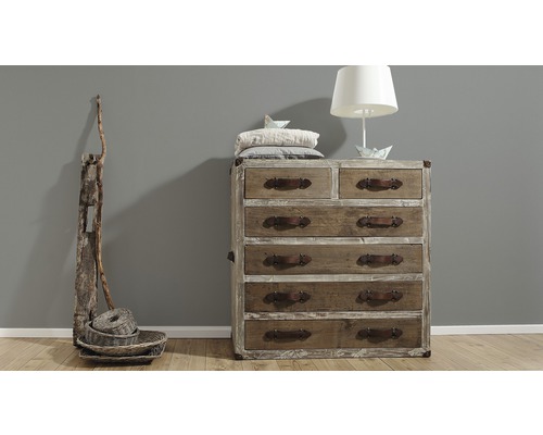 Dřevěná komoda se šesti zásuvkami, lampou a dekorací v místnosti.