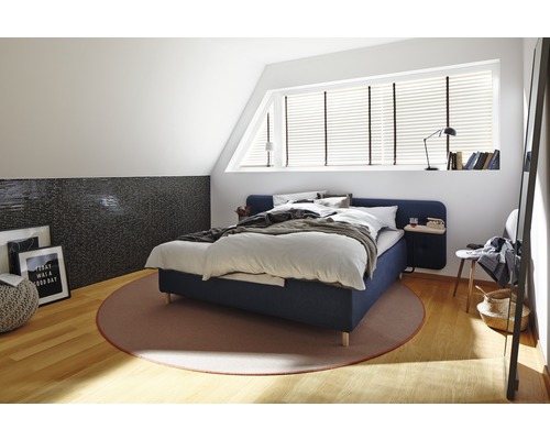 Ložnice s postelí, kobercem a dekorativními prvky v světlém podkroví