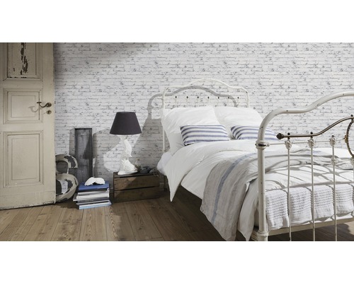 Světlá ložnice s postelí před tapetou s cihlovou zdí