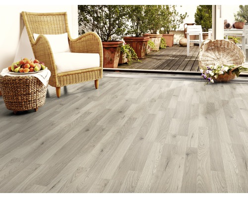 Světlá místnost s laminátovou podlahou, ratanovým křeslem a hrnkovými rostlinami na balkoně