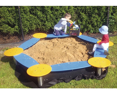 Pískoviště se sedacími prvky a hrajícími si dětmi na zahradě