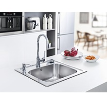 Nerezový kuchyňský dřez s baterií a dávkovačem saponátu ve světlé kuchyni.