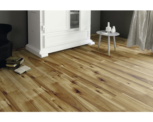 Položená laminátová podlaha v obývacím pokoji se skříní a stolem.