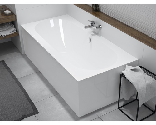 Vestavěná vana ve světlé koupelně s armaturami a ručníky.