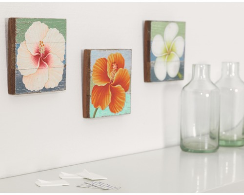 Dekorativní nástěnné obrazy s květinovými motivy a skleněné lahve na stole