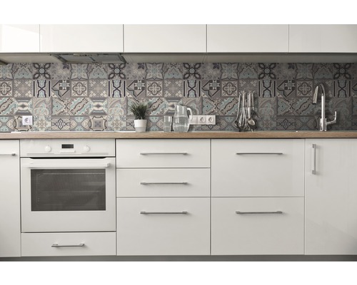 Světlá kuchyně s bílými skříňkami, dřevěnou pracovní deskou a obklady v patchworkovém designu