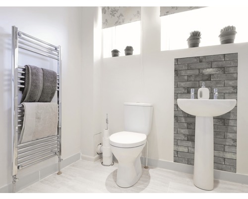 Světlá koupelna s toaletou, umyvadlem, radiátorem a ručníky.