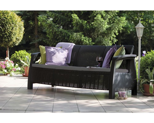 Zahrada: Černá ratanová pohovka s polštáři, dekou a sklenicí vína na terase