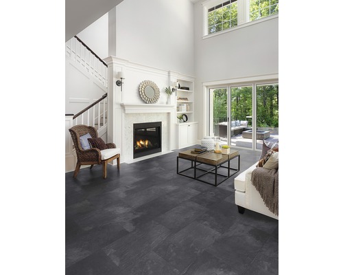 Světlý obývací pokoj se schodištěm, krbem a tmavou dlažbou.