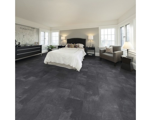 Ložnice s postelí, komodou, křeslem a podlahou s kamenným vzhledem