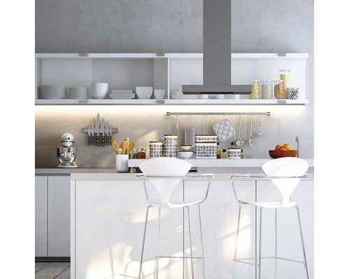 Světlá kuchyně s bílými kuchyňskými skříňkami, odsavačem par a barovými stoličkami.