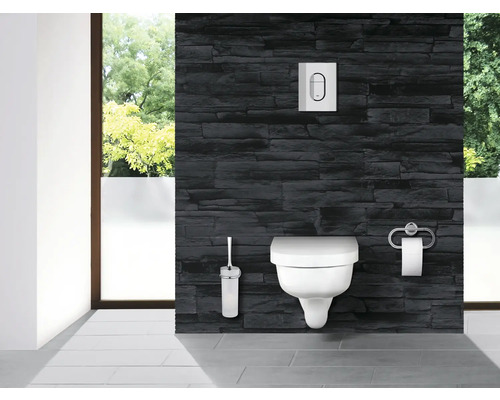 Moderní koupelna se závěsným WC, ovládacím panelem, WC štětkou a držákem toaletního papíru před kamennou stěnou
