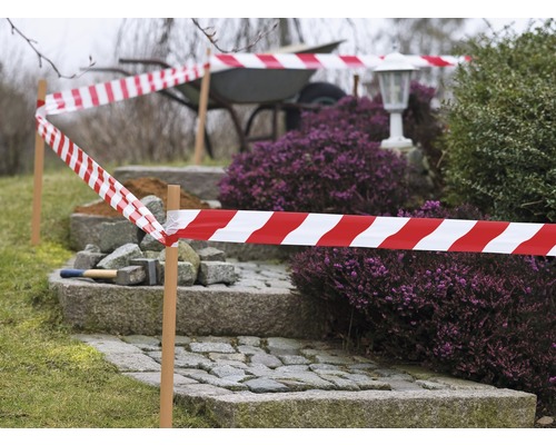 Zahrazená zahrada s červenobílou výstražnou páskou a schody z dlažebních kostek