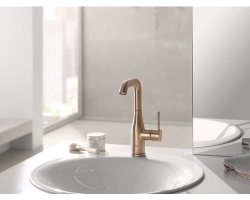 Na umyvadle stojí zlatá vodovodní baterie vedle umyvadla.