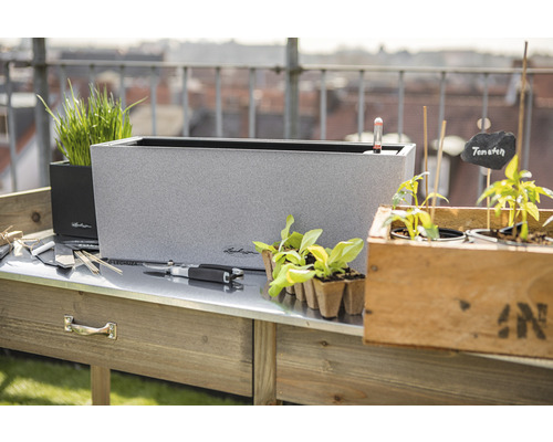 Scéna s osazovacím stolem, květináči a zahradním příslušenstvím pro venkovní použití.