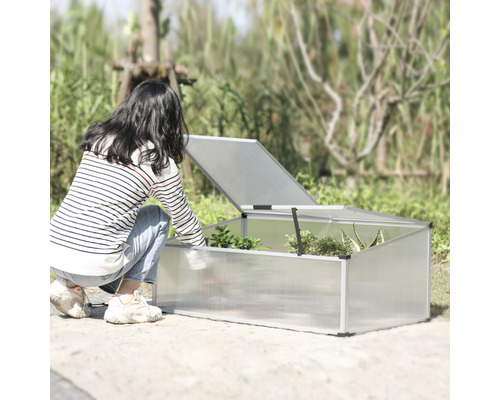 Žena se sklání k pařeništi s otevřeným víkem na zahradě.