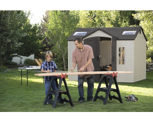 Otec a syn měří dřevo na staveništi na zahradě před kůlnou na nářadí.