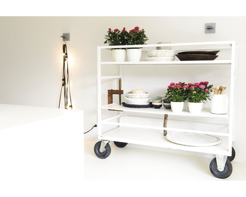 Bílý pojízdný regál s květináčemi, miskami a dekorativními předměty ve světlé místnosti.