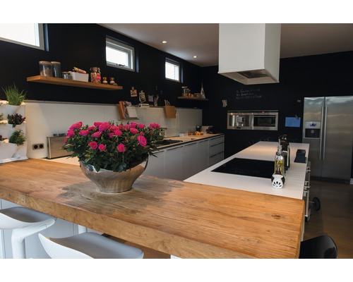 Světlá kuchyně s dřevěnou pracovní deskou, kuchyňským ostrůvkem, černými stěnami a dekoracemi