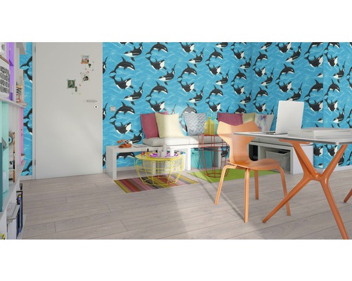 Moderní pokoj s tapetou zobrazující vzor velryby, stůl s notebookem, židle a police.