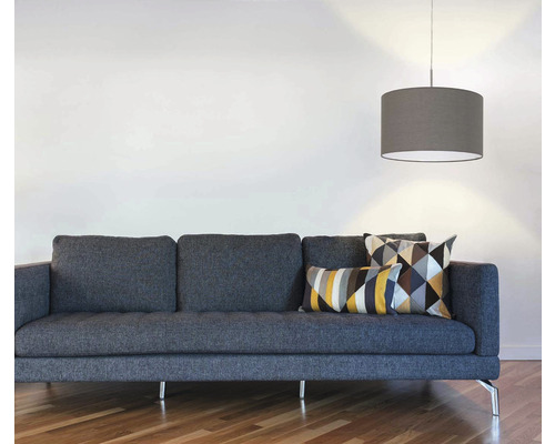 Obývací pokoj s šedou pohovkou, geometrickými polštáři a závěsnou lampou