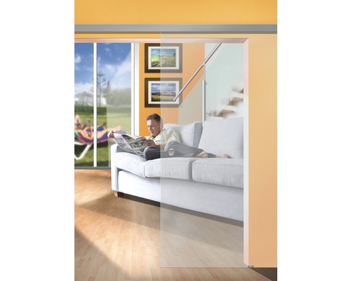 Obývací pokoj se skleněnými posuvnými dveřmi, pohovkou a mužem čtoucím si