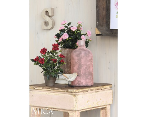 Dekorativní scéna s umělými květinami, ptákem a vázou na stole