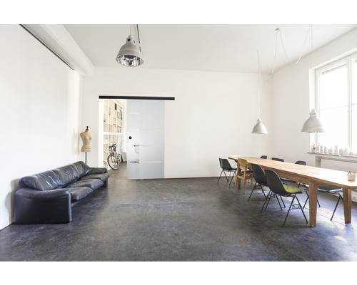 Světlá místnost s pohovkou, stolem, židlemi a skleněnými posuvnými dveřmi