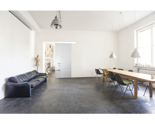 Interiérová fotografie světlé místnosti s pohovkou, jídelním stolem a posuvnými dveřmi