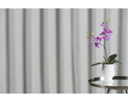 Dekorativní fialová orchidej v květináči na odkládacím stolku před závěsem