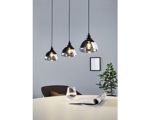 Tři skleněné závěsné lampy nad jídelním stolem.