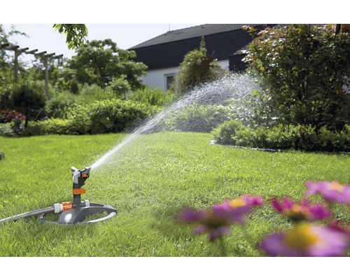 Zahradní zavlažovač zavlažuje trávník na zahradě.