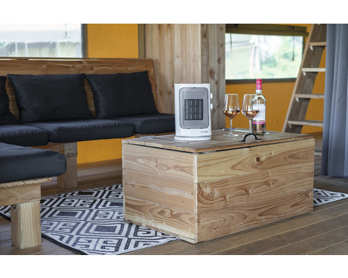 Interiérový pohled s ventilátorovým ohřívačem, lahví vína a sklenicemi na víno na dřevěném stole vedle posezení