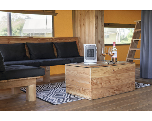 Interiér stanu s dřevěným nábytkem, topným ventilátorem a lahví vína se sklenicemi