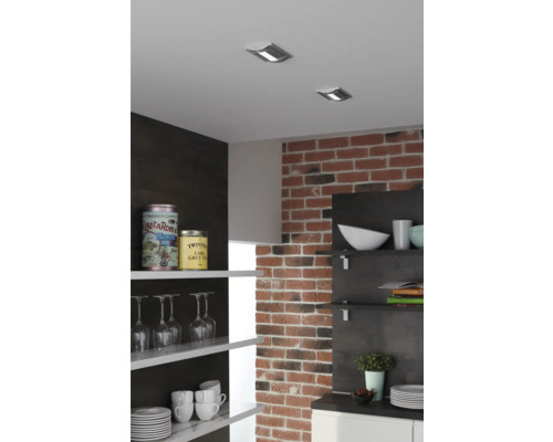 Kuchyňská scéna se stropními bodovými svítidly, cihlovou zdí a otevřenými policemi s nádobím